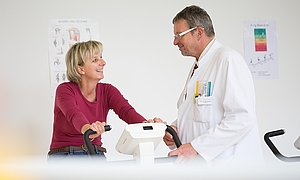 Chefarzt untersucht eine Patientin auf einem Ausdauergerät